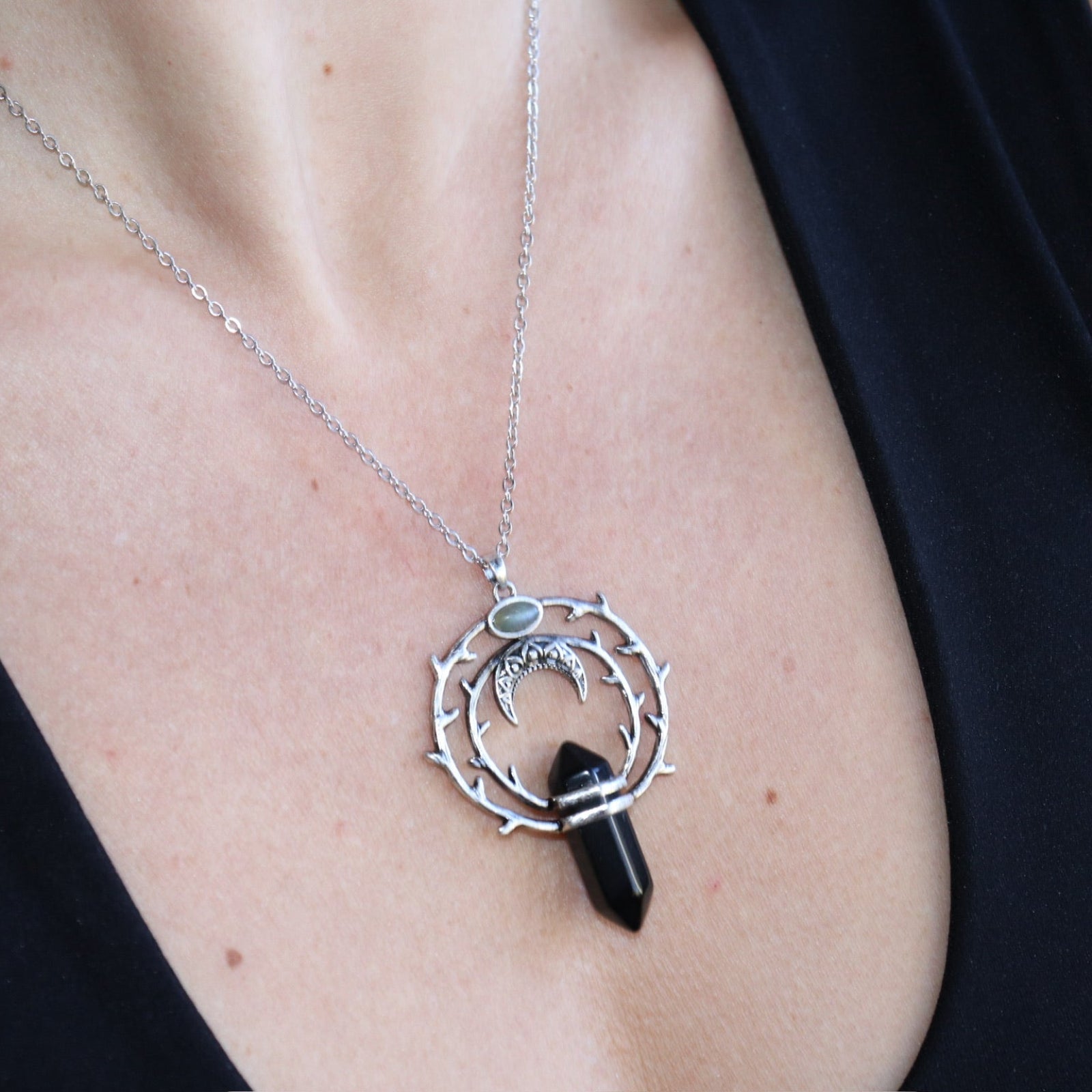 Someone wearing the Silver Thorn Crystal Necklace with a black tank.