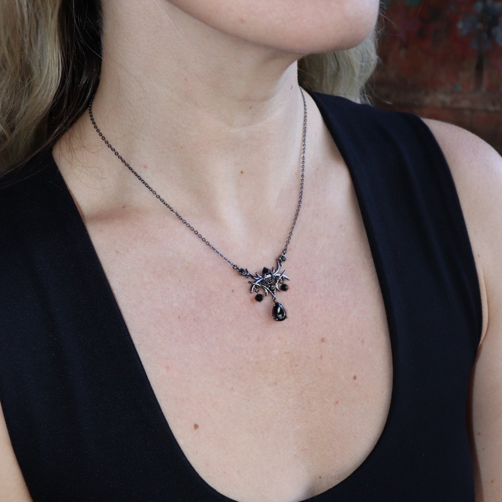 Someone wearing the Dark Fae Brass Plated Necklace with a black tank.