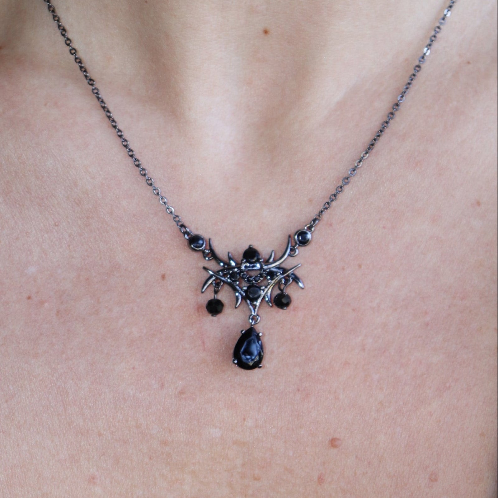 Someone wearing the Dark Fae Brass Plated Necklace with a black tank.
