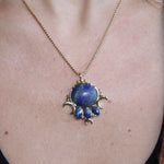 An up-close image of someone wearing the lapis lazuli Priestess Gold Brass Necklace with a black tank.