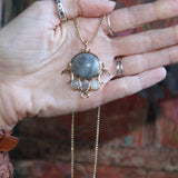 Someone holding the labradorite Priestess Gold Brass Necklace.