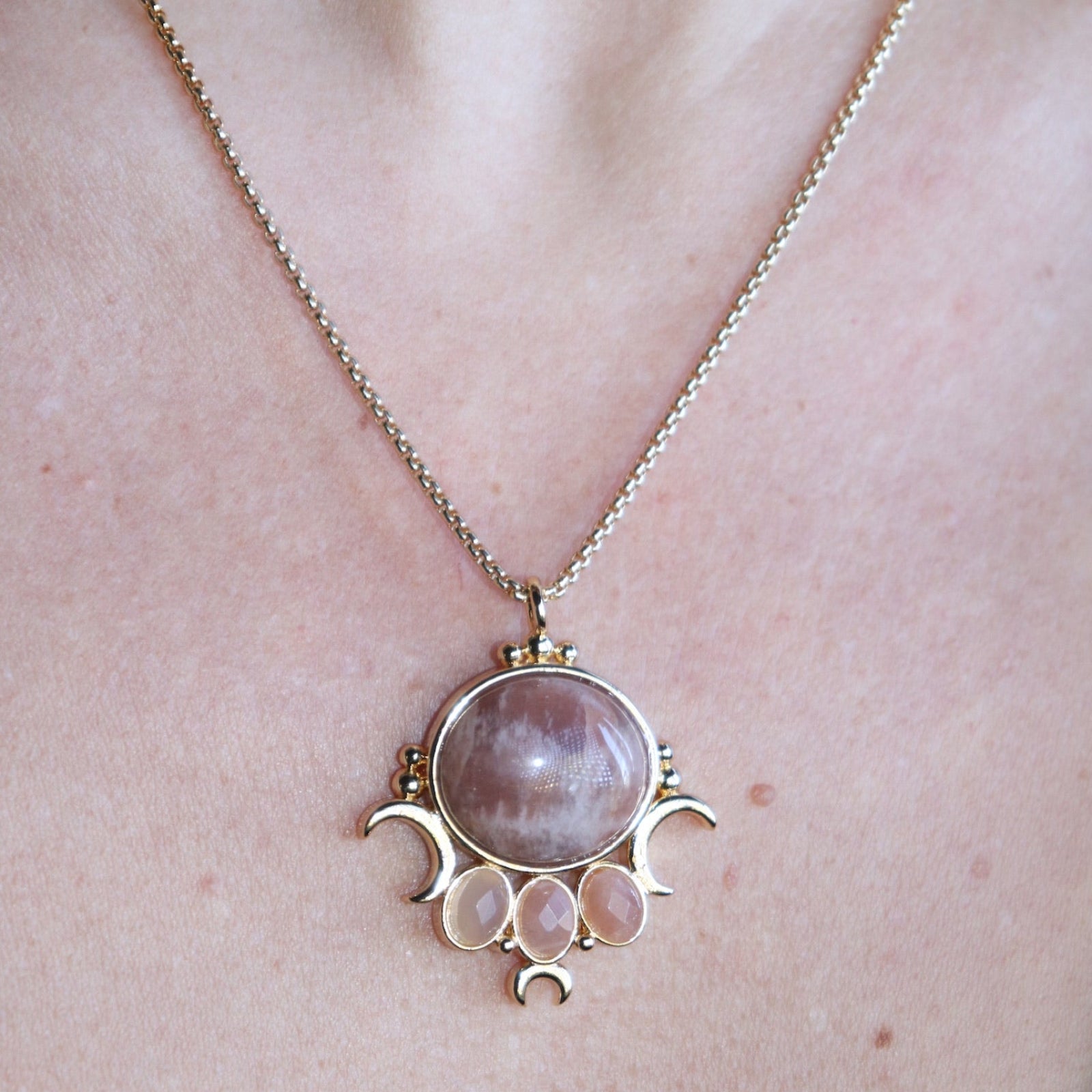 An up-close image of someone wearing the sunstone Priestess Gold Brass Necklace with a black tank.