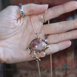 Someone holding the sunstone Priestess Gold Brass Necklace.