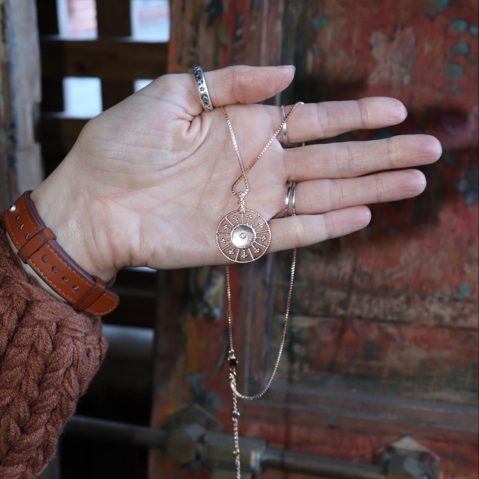 A woman holding the Morgana's Spell Gold Necklace, showing off the back.