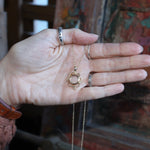 Someone holding the Lilith Keepsake Gold Necklace.