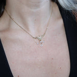 Someone wearing the Fairy Glen Gold Necklace with a black tank and a cardigan.
