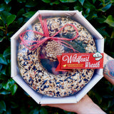 Someone holding the WildFeast Wreath in front of a green bush.