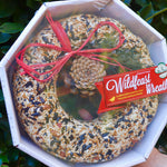 An up-close image of someone holding the WildFeast Wreath in front of a green bush.