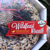 An up-close image of someone holding the WildFeast Wreath in front of a green bush.