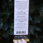 Someone holding the Samhain Premium Incense in front of greenery, showing off the back.