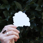 Someone holding the Chibi Huntrix KPop Demon Hunters Inspired Sticker in front of a green bush.