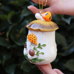 Someone holding the Merry Mushroom 70s Inspired Hand-Painted Retro Ornament in front of a green bush, showing off the side.