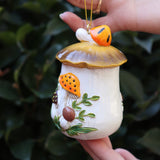 Someone holding the Merry Mushroom 70s Inspired Hand-Painted Retro Ornament in front of a green bush, showing off the side.
