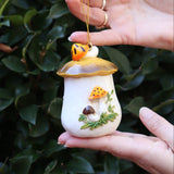 Someone holding the Merry Mushroom 70s Inspired Hand-Painted Retro Ornament in front of a green bush, showing off the side.