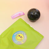 A large Mystery Crystal Sphere Bag open with its contents on a pink and yellow background.