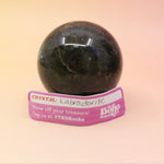 An up-close image of the large Mystery Crystal Sphere Bag's contents on a pink and yellow background.