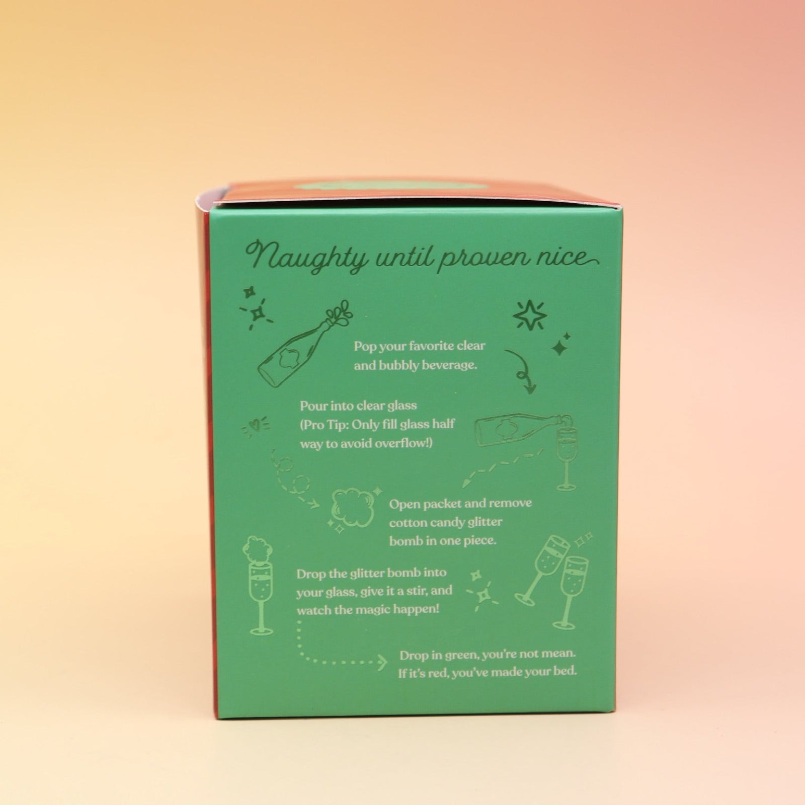 The Naughty or Nice Cotton Candy Drink Glitter Bombs on a pink and yellow background, showing the side.