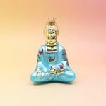 The blue Buddha with Butterfly Glass Ornament on a pink and yellow background.