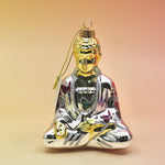 The silver Buddha with Butterfly Glass Ornament on a pink and yellow background.