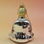 The silver Buddha with Butterfly Glass Ornament on a pink and yellow background, showing off the back.