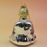 The silver Buddha with Butterfly Glass Ornament on a pink and yellow background, showing off the back.
