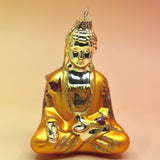 The orange Buddha with Butterfly Glass Ornament on a pink and yellow background.