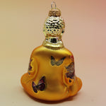 The orange Buddha with Butterfly Glass Ornament on a pink and yellow background, showing off the back.