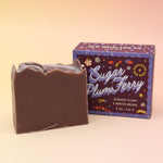 The Sugar Plum Ferry Holiday Bar Soap in front of its box on a pink and yellow background.