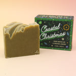 The Coastal Christmas Holiday Bar Soap in front of its box on a pink and yellow background.