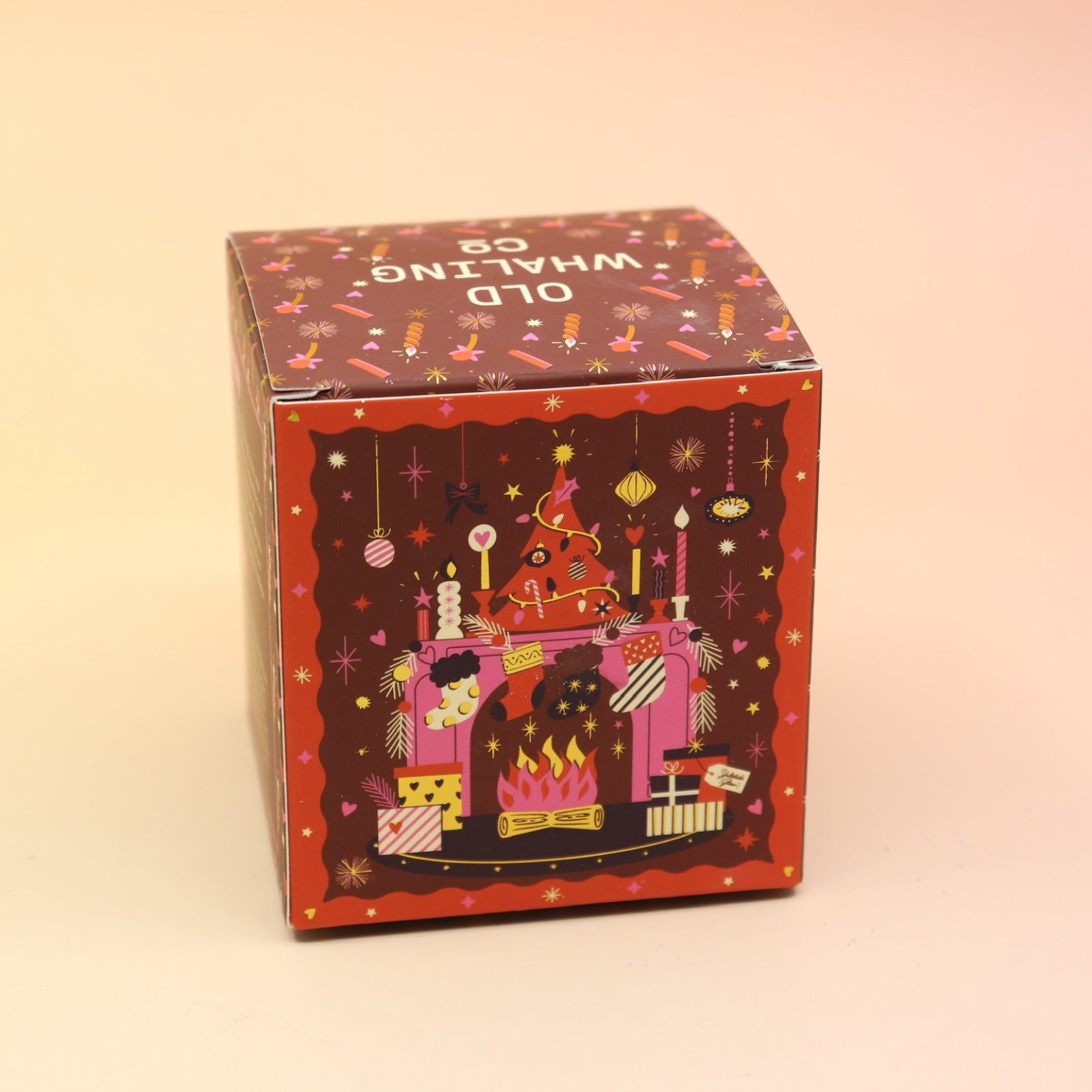 The Yuletide Glow Holiday Bath Bomb in front of a pink and yellow background, showing off the back.