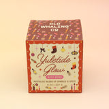 The Yuletide Glow Holiday Bath Bomb in front of a pink and yellow background.