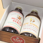 The Winter Survival Gift Set open with the two glass bottles in the box all on a pink and yellow background.