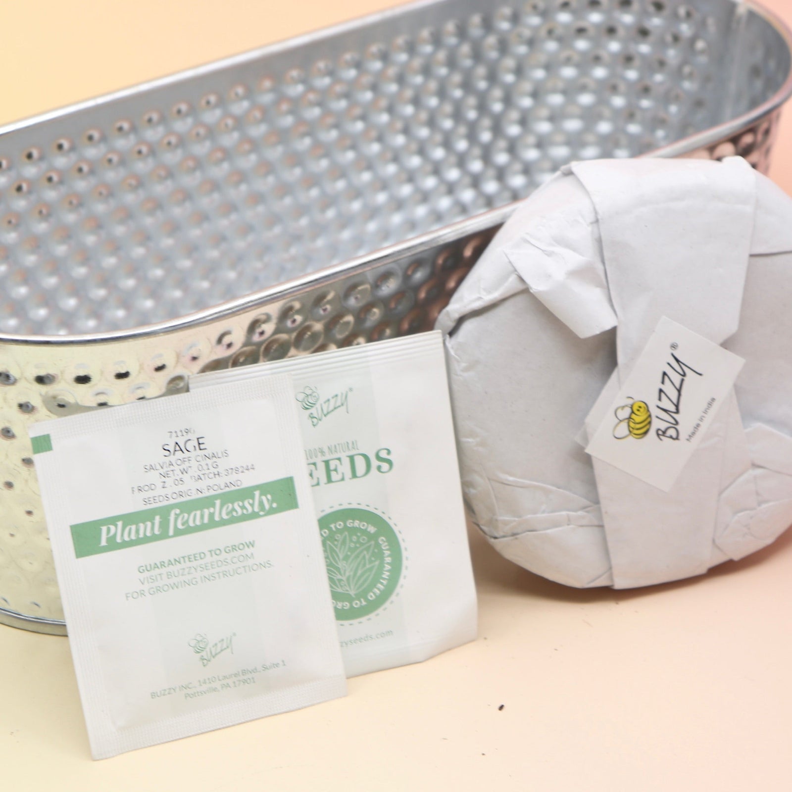 The contents of the Holiday Hammered Windowsill Rosemary & Sage Growing Kit on a pink and yellow background.
