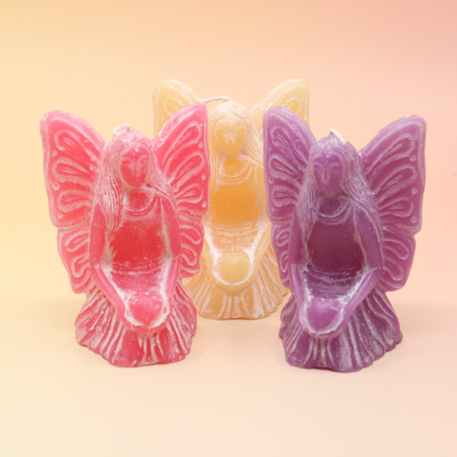 All three colors of the fairy candles on a pink and yellow background.