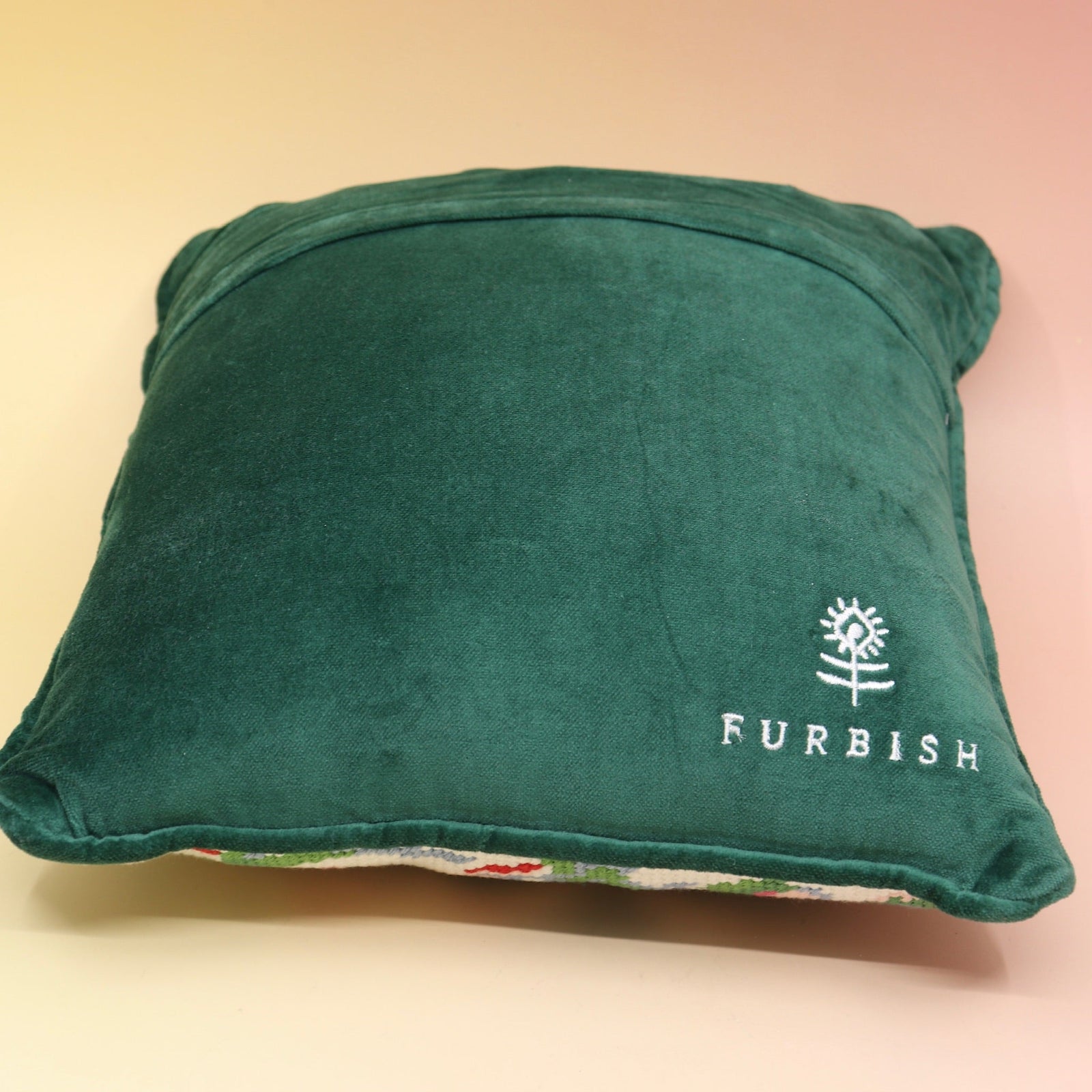 The Bless Your Heart Needlepoint Pillow on a pink and yellow background, showing off the back.