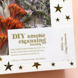 An up-close image of the DIY Smoke Cleansing Smudge Kit on a pink and yellow background.