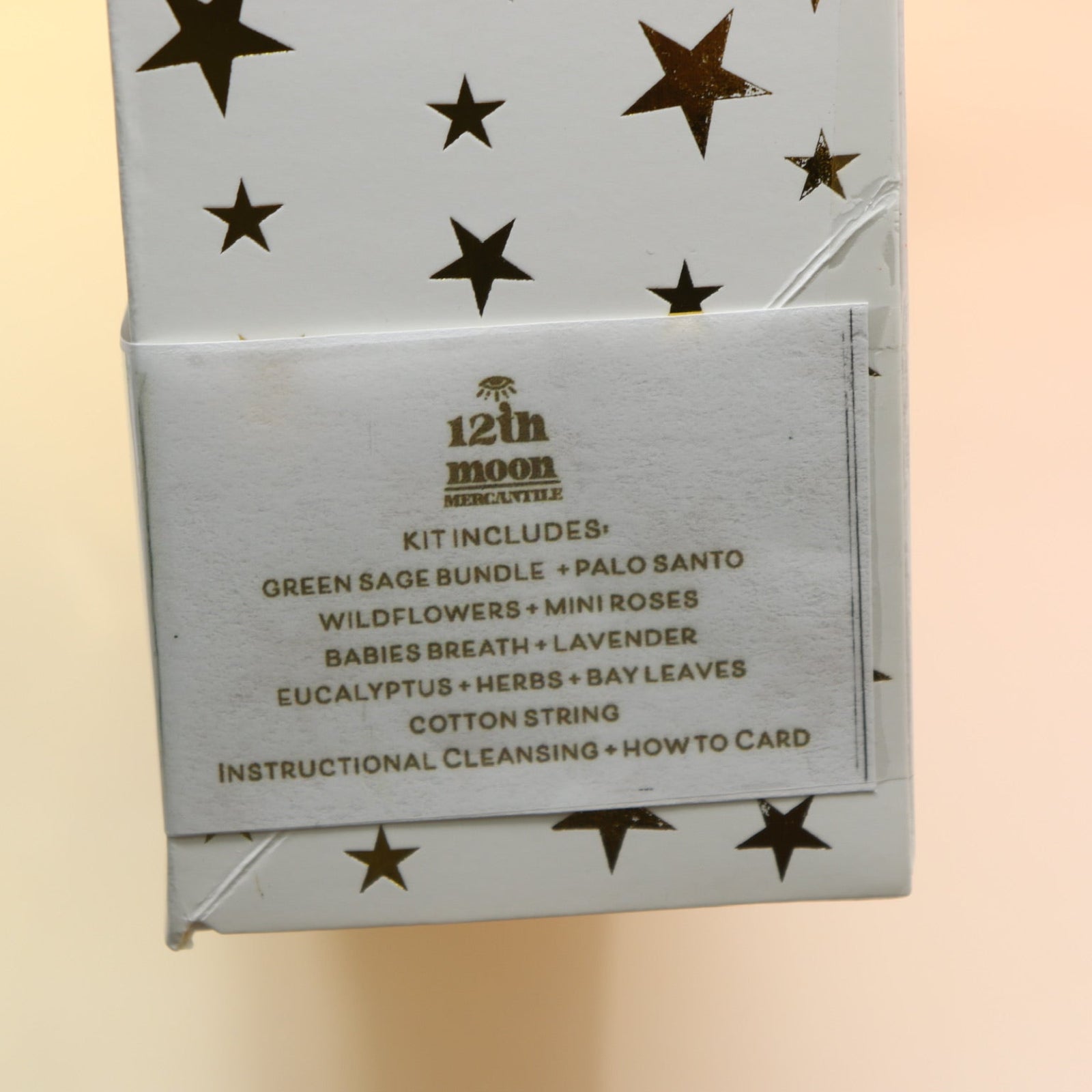 An up-close image of the DIY Smoke Cleansing Smudge Kit on a pink and yellow background.