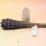 The Lavender Elixir Botanical Smudge Bundle in front of a crystal tower on a pink and yellow background.