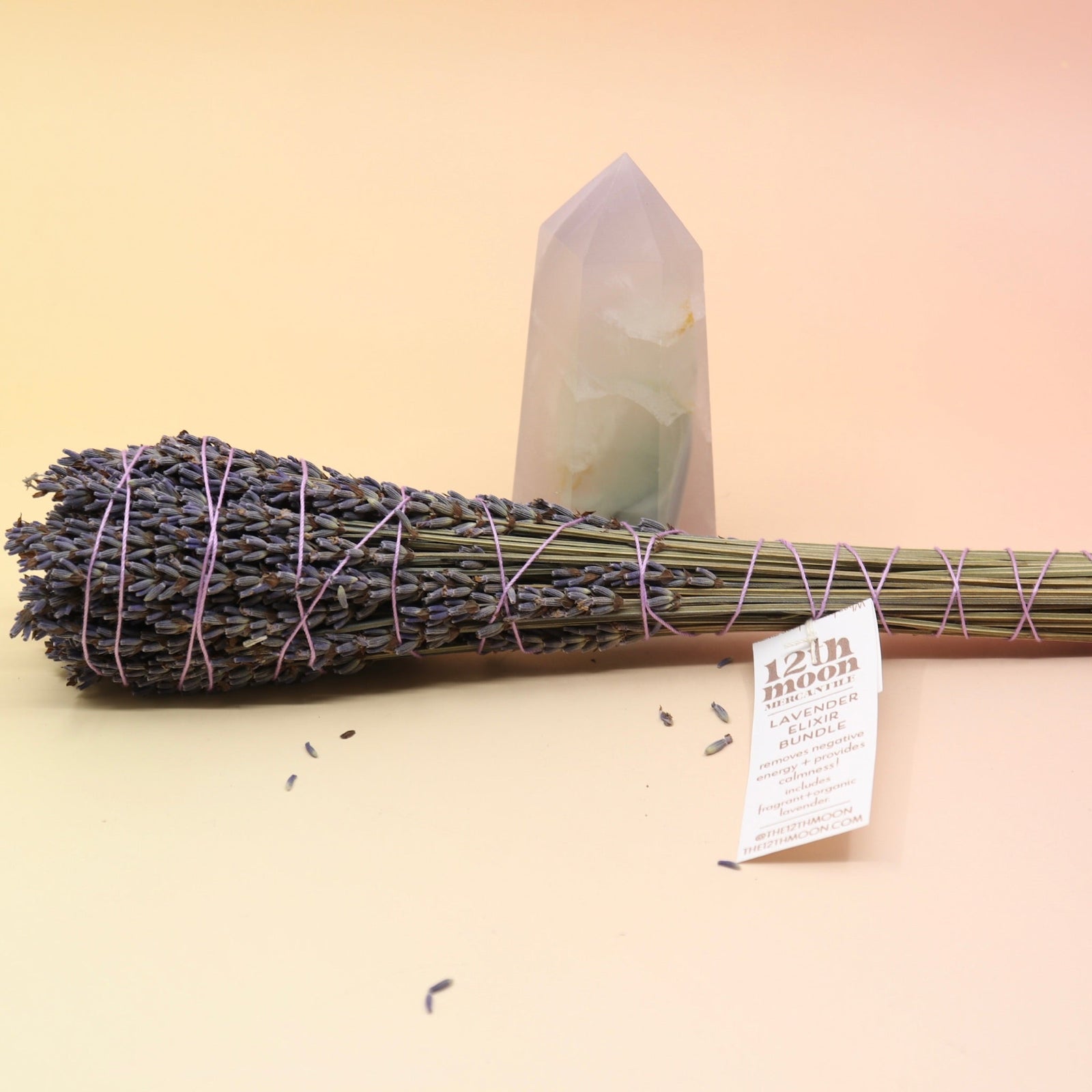 The Lavender Elixir Botanical Smudge Bundle in front of a crystal tower on a pink and yellow background.