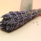 An up-close image of the Lavender Elixir Botanical Smudge Bundle in front of a crystal tower on a pink and yellow background.
