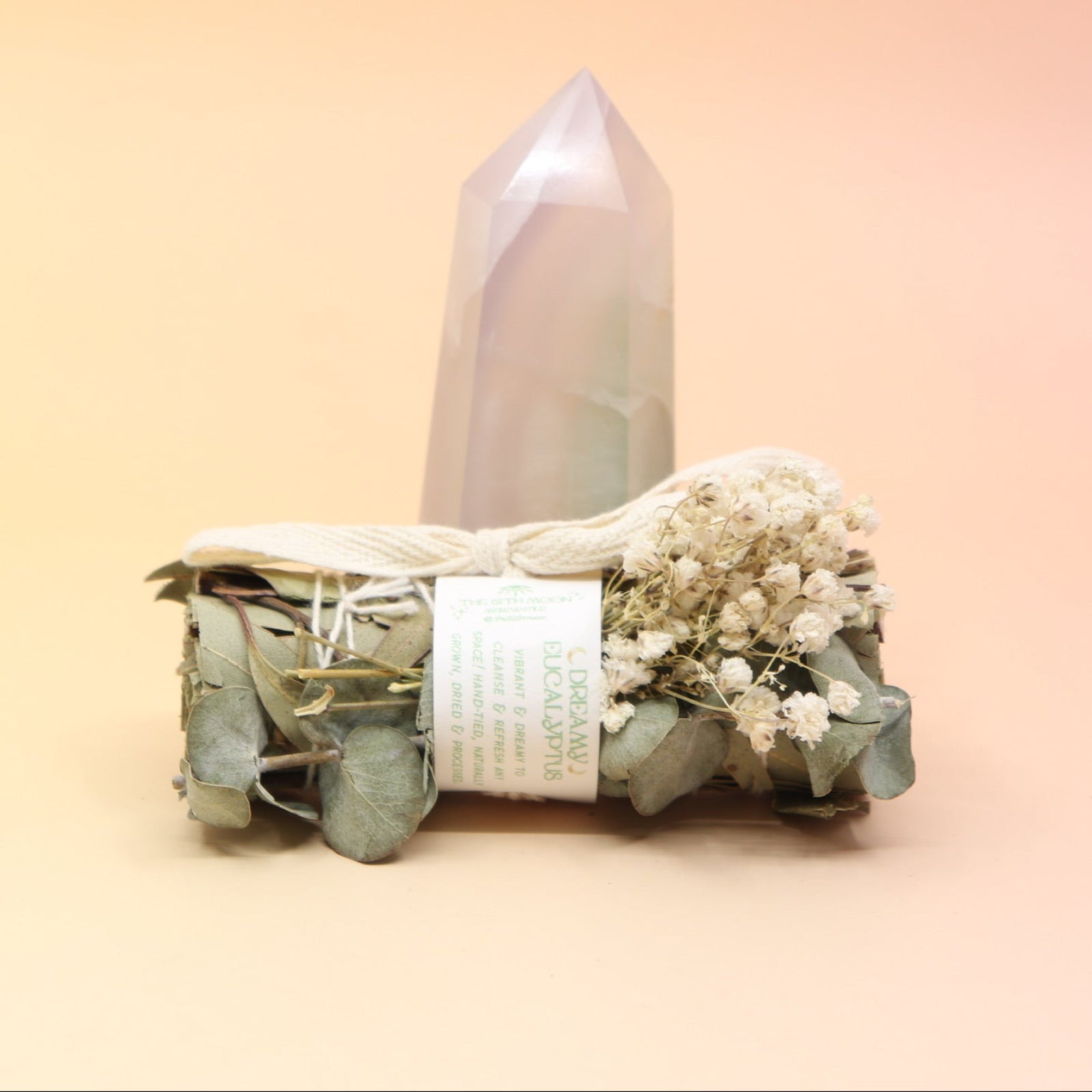 The Dreamy Eucalyptus Cleansing Smudge Bundle in front of a crystal tower on a pink and yellow background.