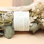 An up-close image of the Dreamy Eucalyptus Cleansing Smudge Bundle in front of a crystal tower on a pink and yellow background.