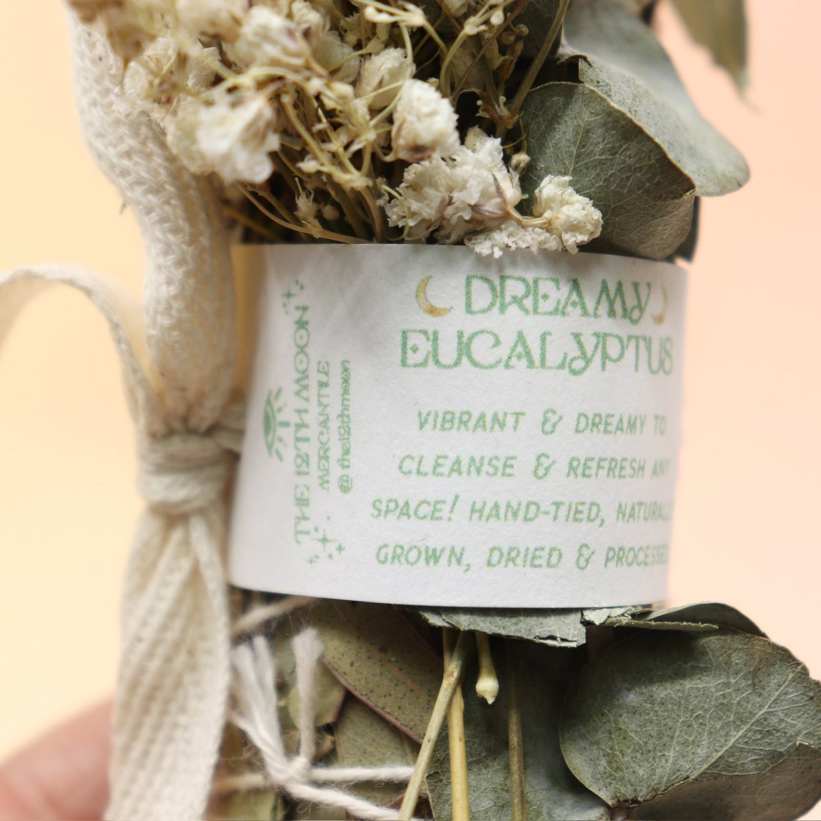 An up-close image of the Dreamy Eucalyptus Cleansing Smudge Bundle in front of a crystal tower on a pink and yellow background.