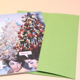 The Never. Christmas Card with its envelope on a pink and yellow background.