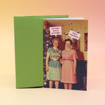 The Act Like We're Not High Christmas Card with its envelope on a pink and yellow background.