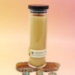 The Pure Beeswax Sanctuary Glass Candle on an agate slice, all on a pink and yellow background.