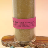 The Rapture Beeswax Aromatherapy Sanctuary Glasses on an agate slice all on a pink and yellow background.