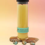 The Awaken Beeswax Aromatherapy Sanctuary Glasses on an agate slice all on a pink and yellow background.