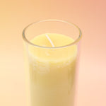 The Awaken Beeswax Aromatherapy Sanctuary Glasses on an agate slice all on a pink and yellow background.