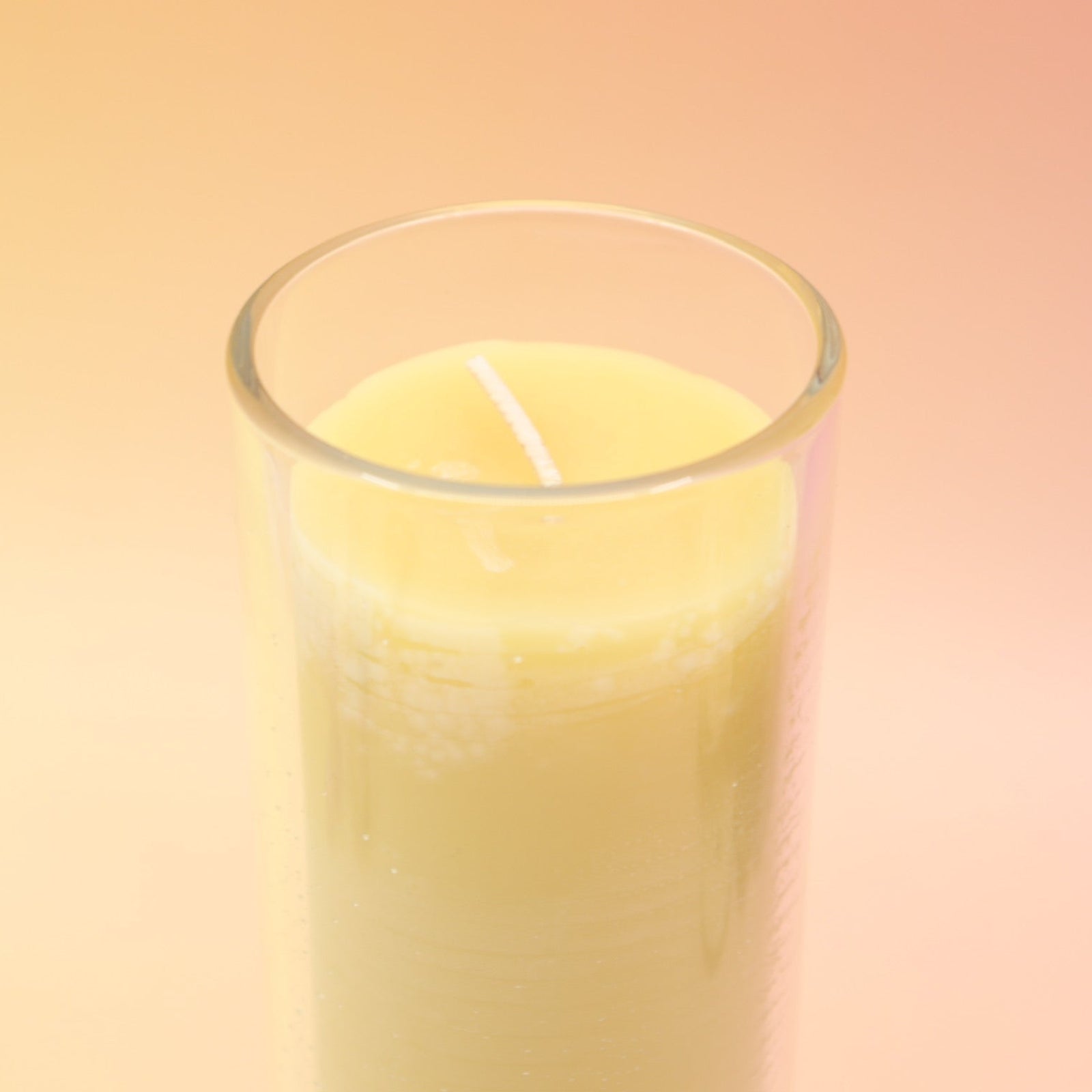 The Awaken Beeswax Aromatherapy Sanctuary Glasses on an agate slice all on a pink and yellow background.